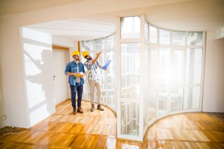 Two young male architects walking through an empty apartment a talking about some changes . Two young male architects walking through an empty apartment a talking about some changes .